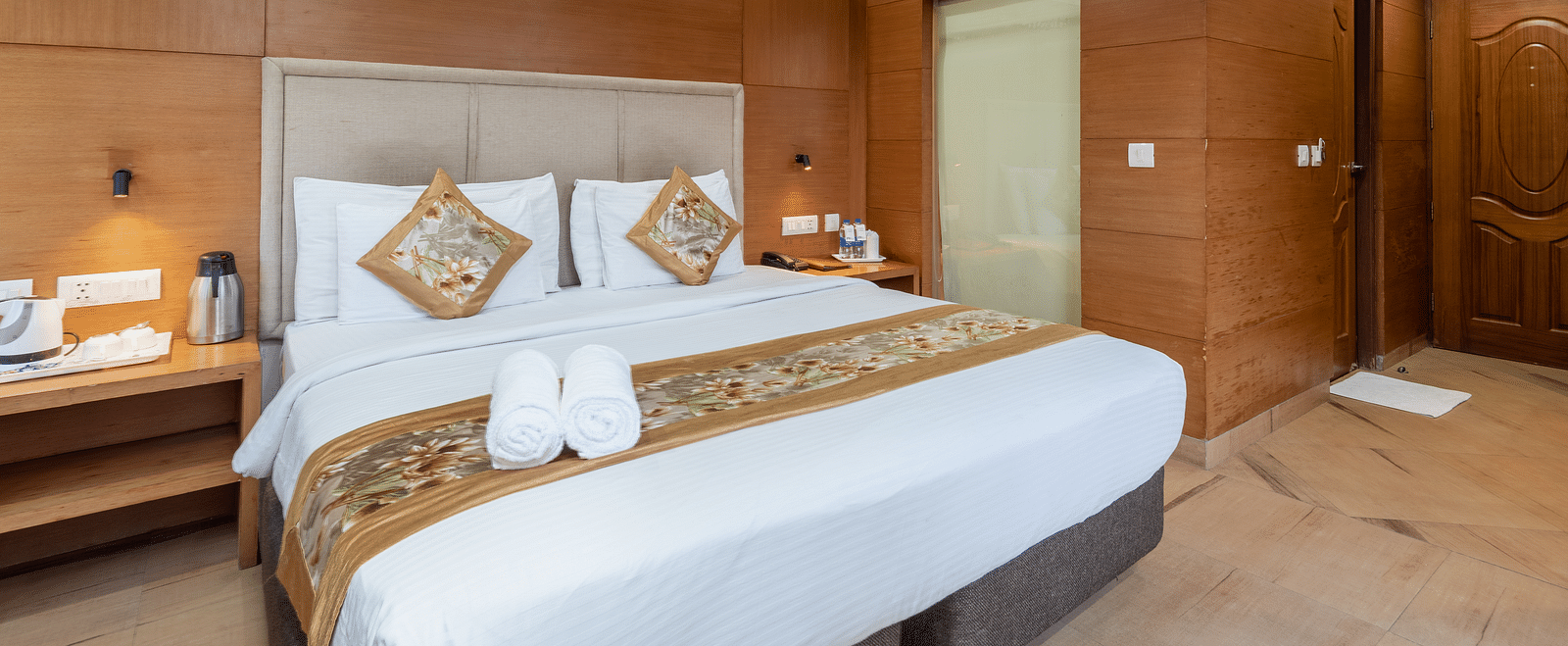 A bedroom featuring a king size bed, and a table with bottled water and a glass at DLS Hotels The Rock Castle.